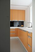 Blick durch Türöffnung auf moderne offene Küche mit orangefarbenen Fronten