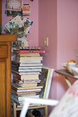 Bücherstapel auf dem Stuhl vor rosa Wand