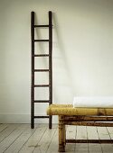 Folded white blanket on bamboo coffee table with  ladder in background