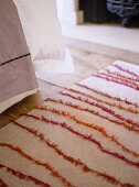 Close up of pink patterned rug on wooden floor in bedroom.