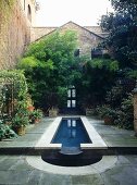 Exterior of brick house with paved patio around water feature.