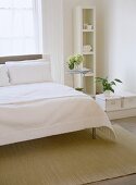 White bedroom with shelving and storage unit.