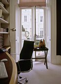 A detail of a modern home office with built in wood desk, chrome and leather chair