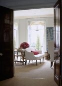 A view through an open door into a traditional sitting room, upholstered sofa, French windows