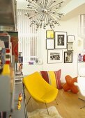 Modern sitting room with white walls, artwork and yellow chair with metal legs.