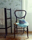 Antique chair with a hat in front of a stenciled wall