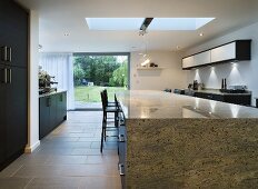 A stone dining table in an open-plan kitchen with terrace windows