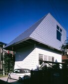 A newly built house with a white facade and a green slate roof