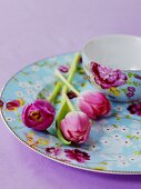 Tulips on a plate next to a matching bowl with a floral pattern