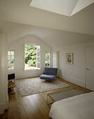 A minimalistic white bedroom with an armchair next to an open terrace door