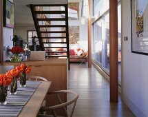 Offener Wohnraum mit Essplatz vor freitragender Treppe und Stützen vor Glasfassade