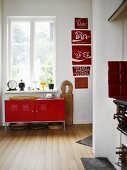 A simple red metal cupboard under a window