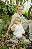 Mutter mit Kleinkind im Wald sitzend