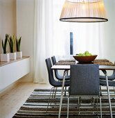 A large pendent lamp above a dining table and chairs