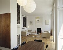 An elegant, modern open plan living room with a dining table and paper pendant lamps