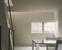 Minimalist living room with stairway and table with chair in front of window