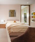 Double bed with light yellow bed linen and bright patterned wallpaper on the wall