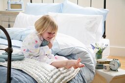 Little girl in pajamas sitting on the bed