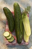 Fresh cucumbers, whole, halved and slices, on tea towel