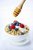 A bowl of muesli with fresh berries, yogurt and honey