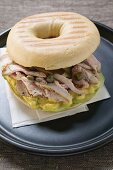 Pork fillet, capers and mustard relish in bagel on plate