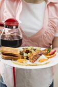 Waitress serving bacon, egg and hash browns and coffee