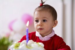 Small girl blowing out candle on kiwi coconut cake