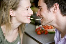 Young couple eating the same strand of spaghetti