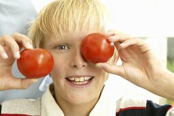 Blonder Junge mit zwei Tomaten