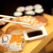 Hand taucht Sushi in Sojasauce