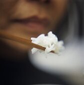A Person Holding Rice on Chopsticks
