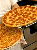 A Man Holding Two Fresh Baked Pizzas