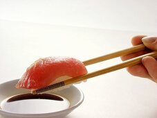 Stäbchen halten Maguro Sushi über Sojasauce