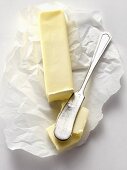 Stick of Butter Resting on Paper with Butter Knife