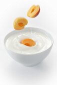 Apricots falling into a bowl of yogurt
