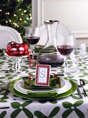 A table laid in green and white for Christmas with red wine