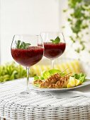 Chicken Satay and berry ice cream with mint in stemware glasses