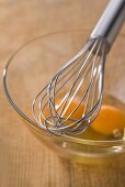 Whisk and egg yolk in a glass mixing bowl