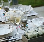 A table laid with glasses of wine and flowers in glass containers