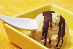 A scoop of banana ice cream with chocolate sauce
