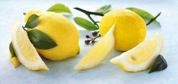 Whole lemons, lemon wedges and lemon leaves