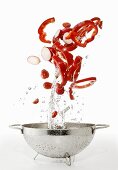 Peppers, tomatoes and radishes being washed in a colander