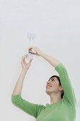 A woman changing a lightbulb