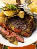 Barbecued ribeye steak with garlic and baked potato