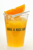 Orange juice in plastic tumbler with wedge of orange