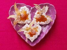 Meringue hearts with physalis & icing sugar on mauve plate