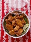 Chicken wings with wedge of lime in aluminium dish