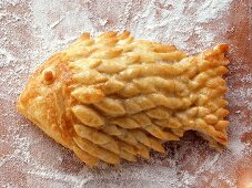Puff pastry fish on floured chopping board