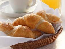 Croissants in bread basket, grapefruit juice & coffee cup