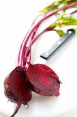 Beetroot with leaves, halved; knife